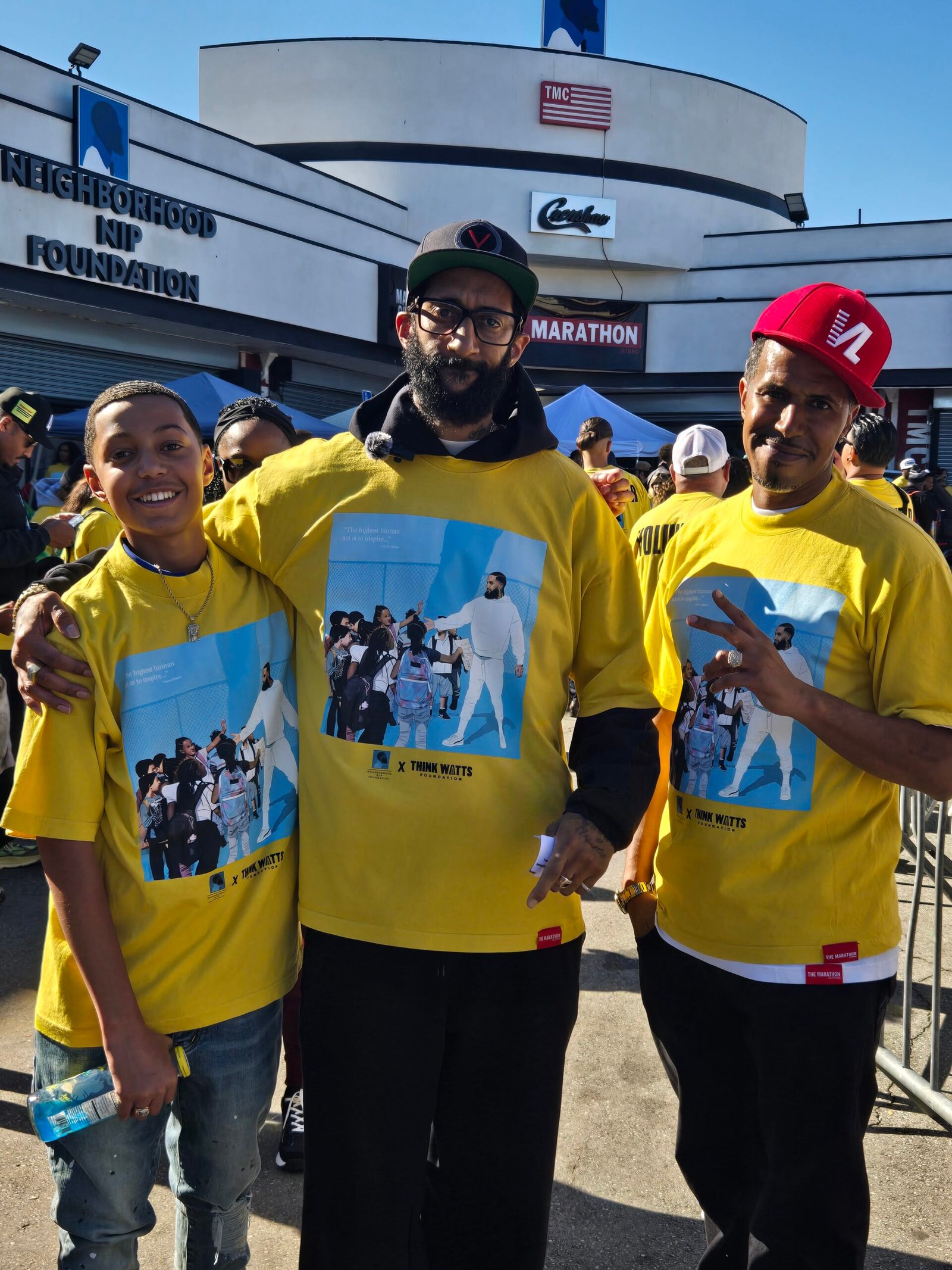 Kelly Morris, MBA and son with Blacc Sam at The Marathon Store during the Nipsey Hussle Square Turkey Drive 2025.