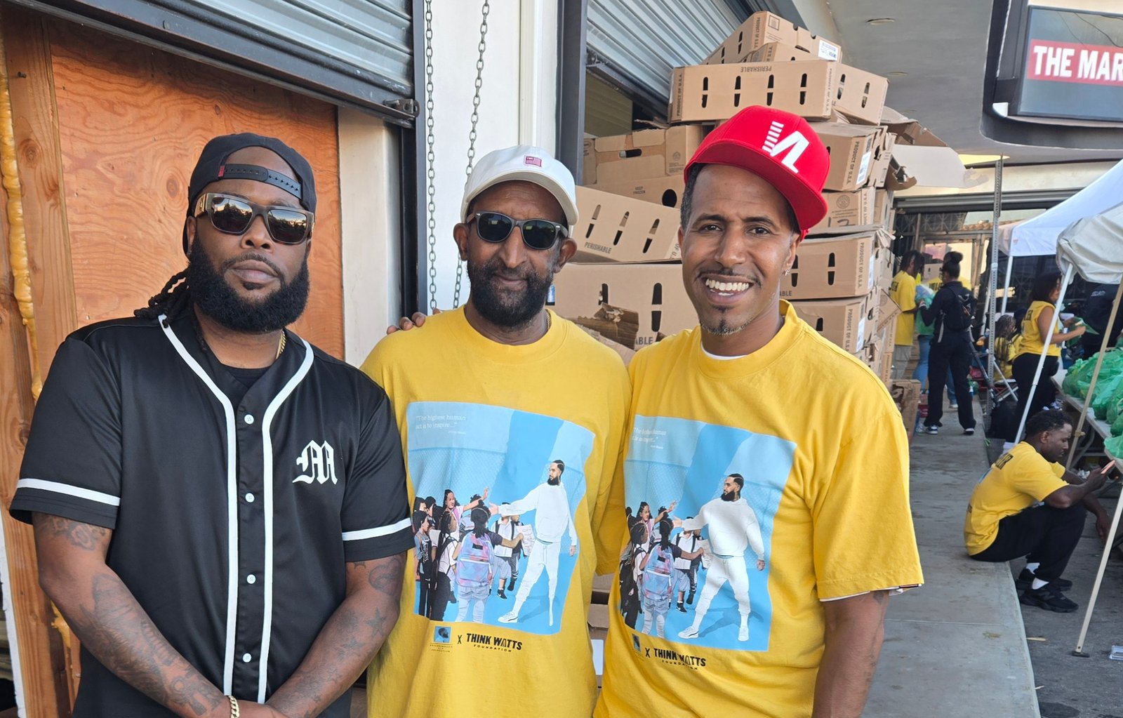 Kelly Morris, MBA and RiMar Clark standing with Dawit Asghedom, father of Nipsey Hussle and Blacc Sam, at The Marathon Store for the Turkey Drive 2025.