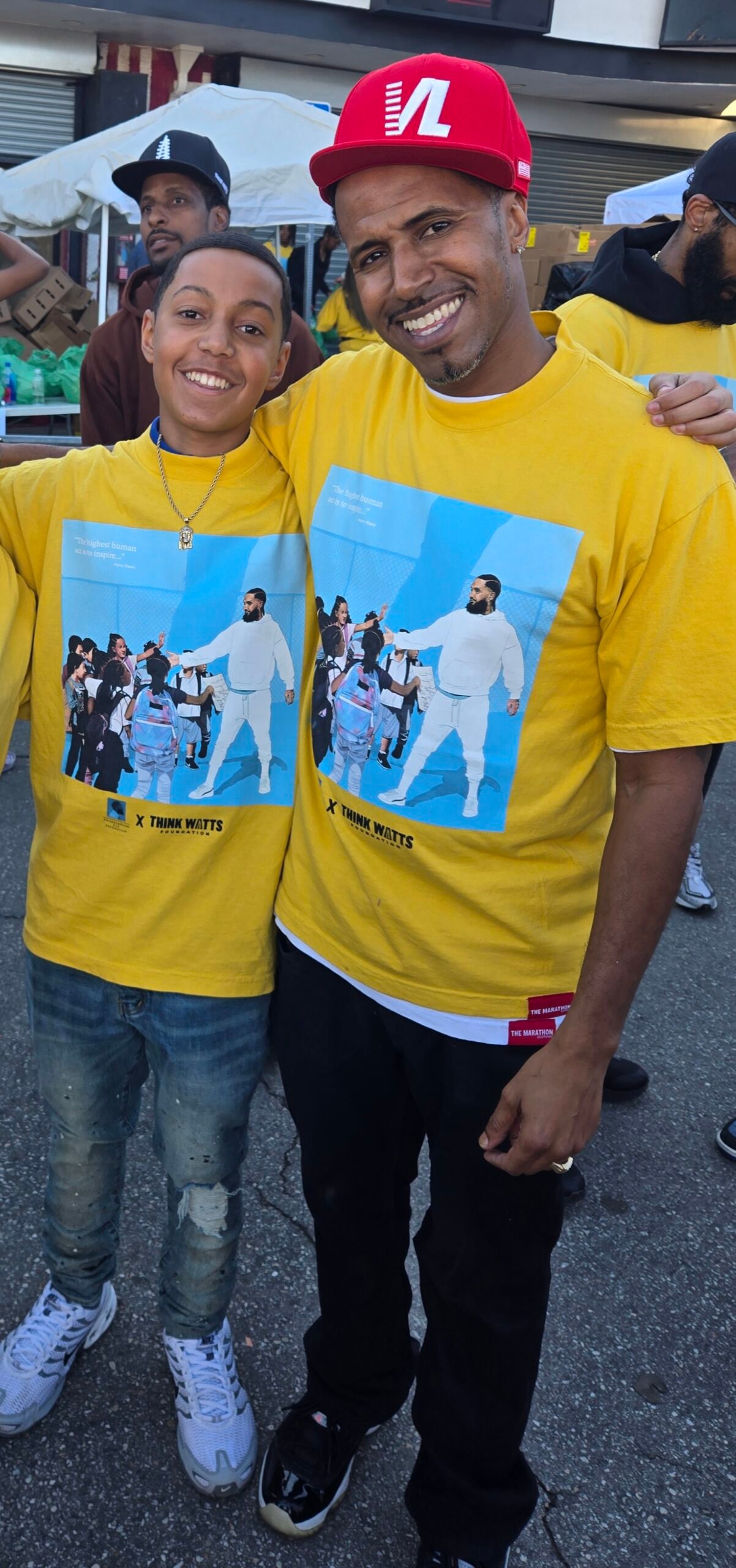 Kelly Morris, MBA and son smiling together outside The Marathon Store during the Nipsey Hussle Square Turkey Drive 2025.