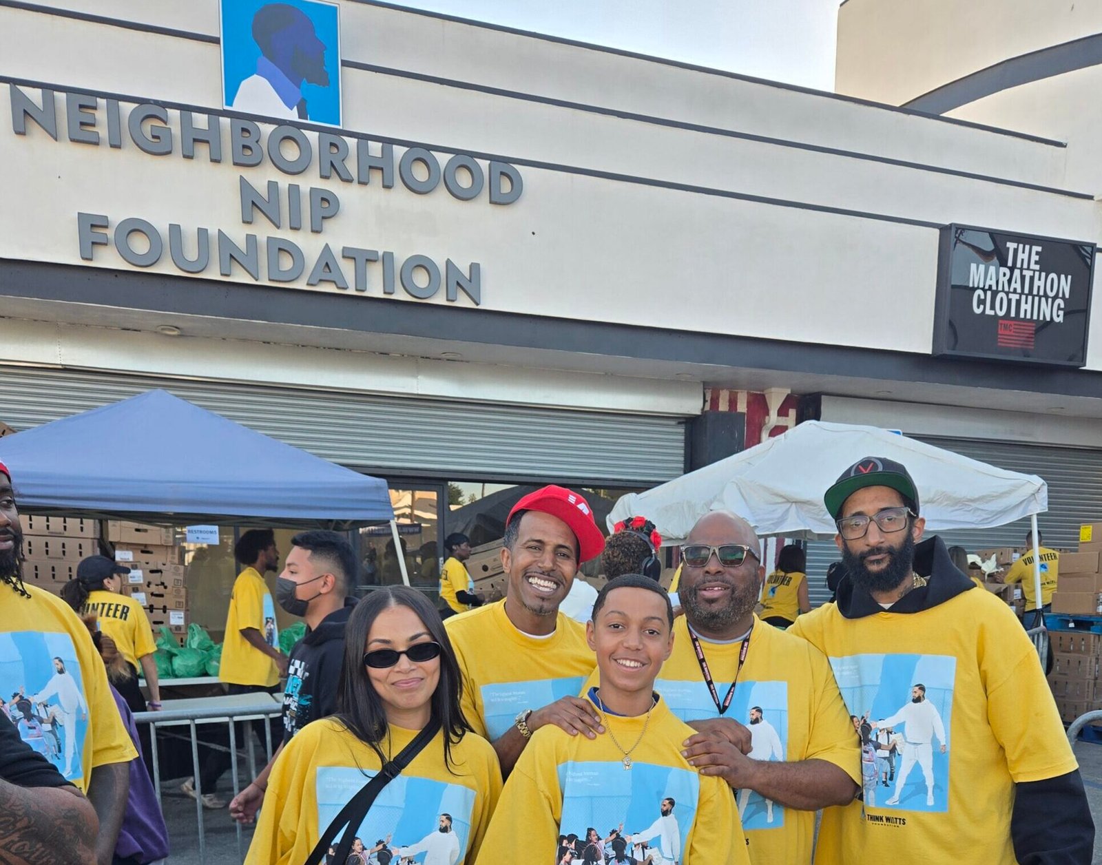 Lauren London, Kelly Morris, MBA and son, Melvin Munir, and Blacc Sam standing together at The Marathon Store during the Nipsey Hussle Square Turkey Drive 2025.